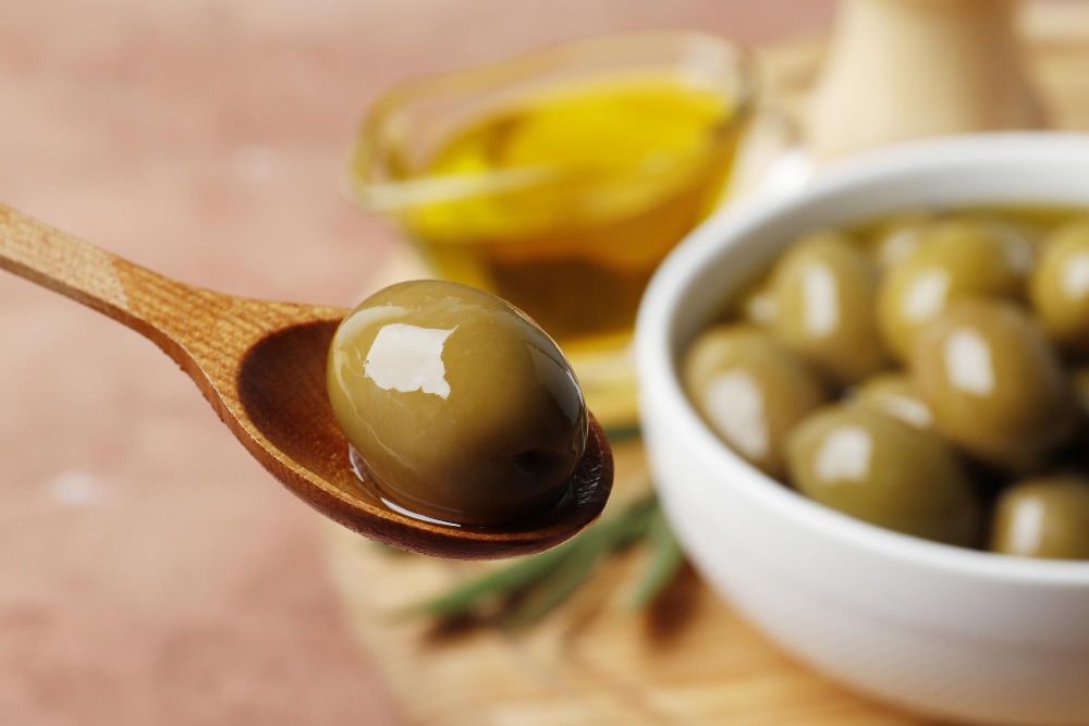 Olive verdi sott'olio su un cucchiaio di legno