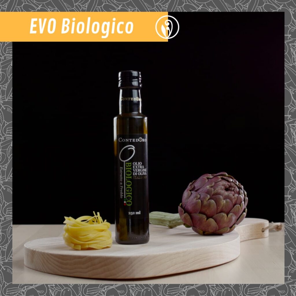 bottiglia di olio EVO Biologico su un tagliere in legno con carciofo e pasta